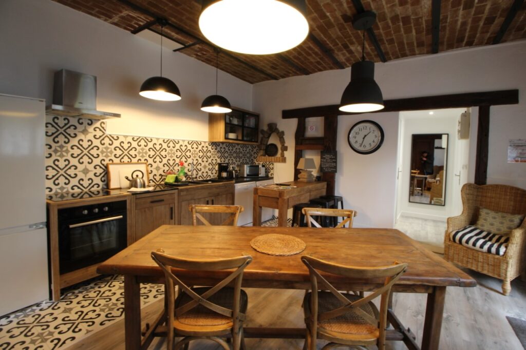 Cuisine conviviale avec grande table en bois et fauteuil en rotin.